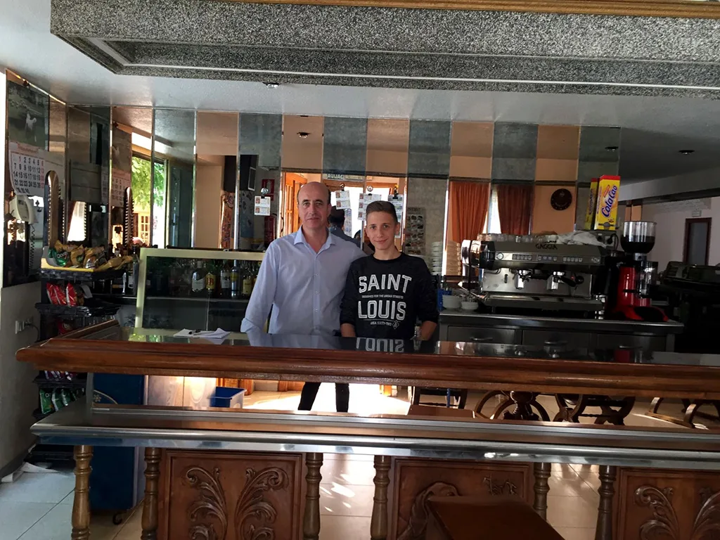 Ein Jugendlicher steht hinter dem Tresen einer Bar mit Kaffeemaschine.